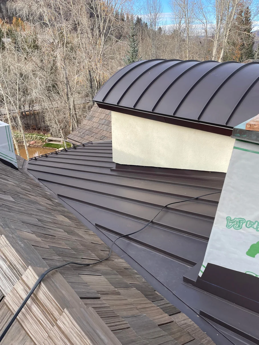 Glen Dee Road Aspen roof with Brava synthetic shake and dark bronze standing seam metal, including a curved metal section and snow guards