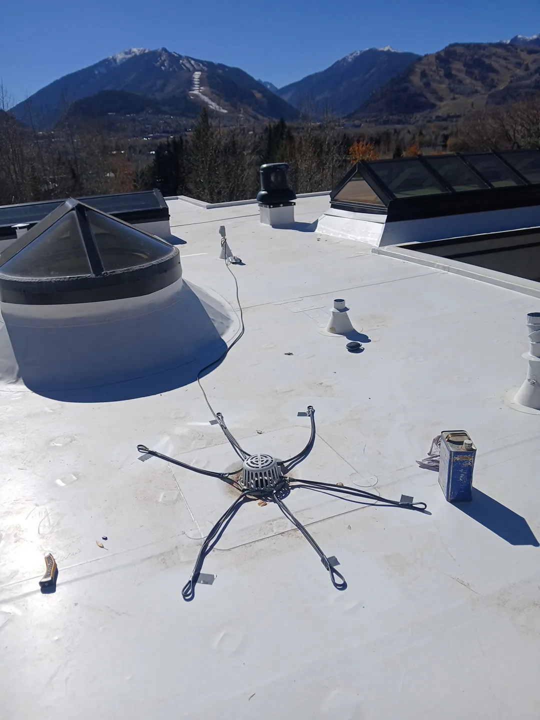 White membrane roof showing flashed skylight curbs, vent penetrations, and mountain views