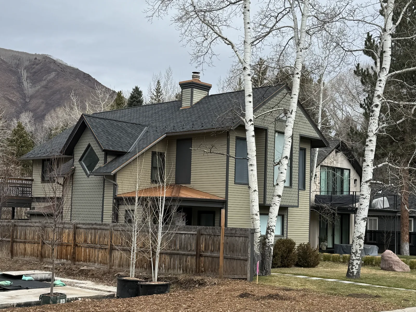 Finished dark Presidential asphalt shingle roof on a mountain home with multiple roof planes and copper accents