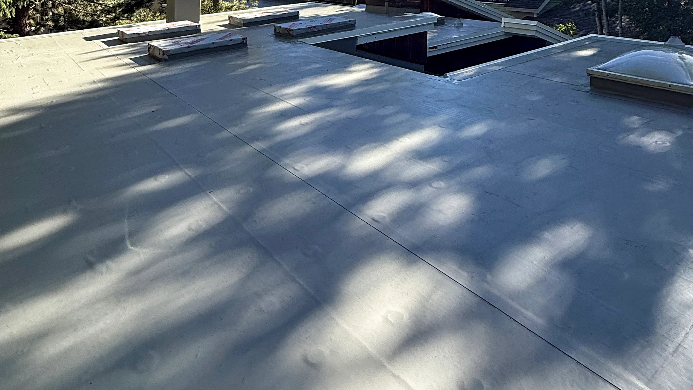 Completed TPO membrane roof with heat-welded seams and flashed roof penetrations